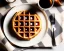 Placeholder: Round waffle with maple syrup plate, plaid napkin, fork