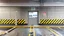 Placeholder: wall design for parking garage, concrete, yellow painted hazard lines, weathering and water stains, in middle is an exit doorway with small window, with a sign is above. rough painted hashmarks and parking lines, add signage found in a parking garage.