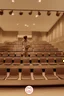 Placeholder: girl with messy bun hitting a punchball. People are sitting around her following the course. She is standing in the middle of the image in the aula.