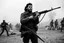 Placeholder: image of Che Guevara standing with heavy gun in hand in a fighting area