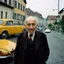 Placeholder: An odd city, traffic, Lutenblag, Molvania, East Europe 1990's, paradoxical, persona vecchia senza denti, brutta, vestita male,