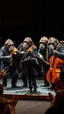 Placeholder: Four chimpanzees musicians wearing Papillons and suits four are playing violins and the one is a playing. Cello each one is looking to a notes stands on a stage, donkey wearing suit standing in front of mic singing in front of them , 4k , high quality picture, many audience are watching and clapping hands