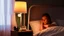 Placeholder: woman in bed with a bedside lamp and a cup of tea on the bedside table