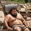 Placeholder: extreme close up photography of a sicilian ugly burly serious wet sweaty, chubby strong fat carpenter, shirtless, boxer, bulge, manly chest, very hairy allover, big goatee 26 years old, curly short hair, sit sleeping with open legs on a little chair , on a construction site in the middle of a road, under the August sun, emotional eyes, , hyper-realistic, photorealistic , frontal view from the ground