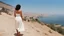 Placeholder: [photo by Russ Meyer] close to the old town of Nazareth, a view on the Lake of Genesareth. a young woman in linen dress, she has her wooden rod she looks at the people down around the shore