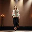 Placeholder: A full-body shot of a beautiful lady wearing azeri folk jacket and pants walking on a nice stage and looking at the camera