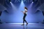 Placeholder: modern stage with gray-blue theme artistic decoration , color full dynamic lighting, a beautiful lady in pants and blouse with sport shoes dancing, 3D recursive fractal structure animating background