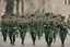 Placeholder: Soldiers marching in formation; military parade; tight formation; shoulder to shoulder; marching along a street; green uniforms; medals and insignia; weapons in hands;