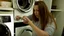 Placeholder: very confused young woman puts a few metal spoons into the household dryer