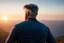 Placeholder: a brawny man with grey hair views sunset from a cliff