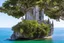 Placeholder: A futuristic ruined gothic building on an island floating over the sea with balconies, verandas, many arches, bridges, spires, paths, trees, dense foliage, spanish moss, ivy, blue sky, white clouds