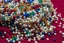 Placeholder: close-up high res photo by Barry Webb: a gypsy's wrist surrounded and saturated by strings of pearls, the hundreds of pearls in every color shaped like dice or skulls. It's the childlike, mortal symbol of chance intertwined with destiny.