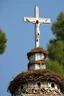 Placeholder: on top of the stone statue of the crucified Jesus is a huge stork's nest with storks