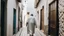 Placeholder: Rear view of an elderly Moroccan walking in a Moroccan alley with white walls