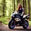 Placeholder: Very attractive woman sitting on a motorcycle. The bike is Yamaha. In the background is a forest.