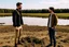 Placeholder: A picture of two people exchanging criticism in a constructive and respectful manner, standing on a land surrounded by dirt, and behind them a lake