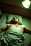 Placeholder: man lying on back on motel bed, arms at sides, face partially turned away, neutral expression, unresponsive posture, plain bedding, generic sheets, harsh flash lighting, dim uneven room lighting, off center framing, candid documentary photo, slightly grainy, no emotion