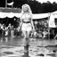 Placeholder: alluring young Dolly Parton on stage at Woodstock, she is 19 years old, Woodstock is well of mud and beatnik attendees, her long wavy blonde hair and her square jaws make her unique, she stands up with muddy sandals