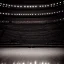 Placeholder: a single chair on stage under spotlight close up view facing empty audience at a dark and empty symphony hall