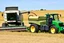 Placeholder: Parked at the edge of a field is a Claas brand Combine and a John Deere Tractor with seeder