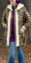 Placeholder: Image shows wholly a Brunette. average body type. Mantle is sewed of recycled Denim and sewed together of camouflage pieces. Camouflage colors are orange,terracotta, cream and purple. Cream latex gaiter. Big bright purple/khaki felt tippet and cream or blue or lilac colored-hood. mantle is merged with satchel. . AKG-style headphones (gold rings!) is merged with small felt cap with small visor. Style: Haute Couture in 1936, Paris fashion in 2023, inspired by street art.