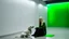 Placeholder: A woman with ash-blonde hair sits on the bright green floor of a concrete room, petting a long-haired white dog. The room has a minimalist aesthetic with light concrete walls and dark openings leading to other areas.