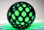 Placeholder: beautiful composition, black spheres with holes, woven of thin black wire, the entire surface of the sphere is filled with symmetrically arranged round holes, from the inside of the sphere a bioluminescent blue-green (sometimes blue, sometimes green) light is emitted, projecting coloured round spots onto the whole background and the whole horizontal base where the sphere is placed. S<AI