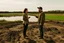 Placeholder: A picture of two people exchanging criticism in a constructive and respectful manner, standing on a land surrounded by dirt, and behind them a lake