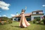 Placeholder: full body close up shot ,country side modern villa wide yard in front of villa ,a beautiful lady in nice long dress dancing,flowers blue sky ,petty clouds