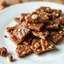 Placeholder: A full-view image of Knäck, Swedish toffee 🍬 with a crunchy texture, broken into pieces on a plate, garnished with a few nuts.