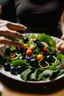 Placeholder: A plate of salad and pasta, with hands placing black olives on top of them