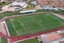 Placeholder: Cândido de Oliveira" Football Stadium, an aerial photograph taken by a drone in a futuristic landscape in an abandoned Alentejo village with white neon light, Shot on Canon EOS R5, 50mm lens, depth of field, shutter speed 1/ 1000, f/ 2. 8, white balance, 6000k. High resolution, realistic details, HDR efects, film grain, 4K. –ar 16: 10 –