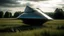 Placeholder: small, sleek, squat, cargo spaceship shaped like a manta ray, sitting in a field