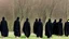 Placeholder: Black robed, hooded monks in the field