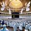 Placeholder: The scene in Mecca: People wearing white Ihram clothes, men without head coverings, women with veils, circumambulating around the Kaaba, and above them are transparent white spirits of children, men, and women with wings revolving around the Kaaba.