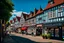 Placeholder: Old English Tudor Street with shops, signs, bridges, and people, sunny day.