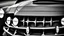 Placeholder: Photograph of a the front grill of a gorgeous, expensive, oldschool black muscle car with a big, black front grill, realistic, stylish, taken up close from the front of the car, symmetrical