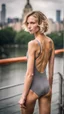 Placeholder: beautiful anorexic young woman, total shot, grey triathlon swimsuit, short blonde wavy bob hair, blurred city background