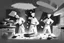 Placeholder: black white storybord, 3 chefs, scattered throughout the kitchen cooking, frying, cutting looking