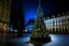 Placeholder: a personified fairy-tale lighted Christmas tree with a big muzzle sits on a bench in front of the city hall in Levice on the square, rolling its eyes and drinking champagne with a mouth whose lips are enlarged with botox as if painted by vincent van gogh