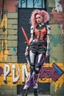 Placeholder: teen woman in retro-futurist cyberpunk costuming with pants and sheathed swords leaning to the side with shoulder against a brick pillar and legs crossed, background is brick with graffiti of a large arrow pointing to the right and text of the word "PUB" on lower left