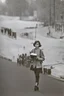 Placeholder: color photo of a student girl 22 years old ,short hair with her books in her hand walking in street,next to trees.