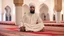 Placeholder: Religious leader, male, 30 years old, at the mosque wearing a turban, traditional Islamic cap, and using a prayer rug.