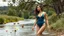 Placeholder: a beautiful lady in nice swim suit in river in country side next to river and big tree,wild flowers standing