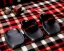 Placeholder: Red plaid slippers on black bearskin rug,log cabin walls, stone fireplace