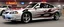 Placeholder: suped up 2004 chevy impala supersport musclecar, silver with black flames outlined with a thin red pinstripe, in front of Sam's club, SuperSport car, impressive, VIP, award winning, detailed