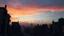 Placeholder: A desolate cityscape at twilight, buildings shattered and overgrown with thorny vines, under a sky streaked with the colors of a dying sunset.