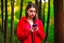 Placeholder: young woman in red clothing standing in a forest holding a smartphone