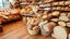Placeholder: The wooden floors of a shop are filled with fancy breads including baguettes, sandwiches, dough and tortillas, white, and whole wheat and wheat ears and sesame seeds and freshly baked sliced ​​breads and a classic theme.