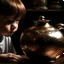 Placeholder: The reflection of a child on the surface of an old copper teapot